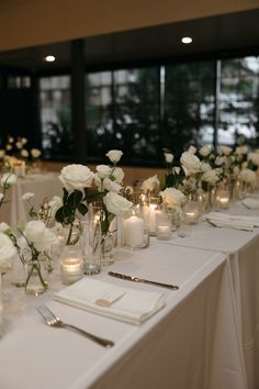 a long table with white flowers and candles on it is set for a formal function