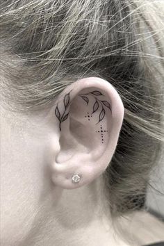 a woman's ear has a small flower tattoo on it