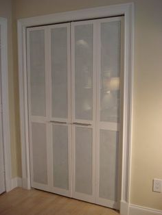 an empty room with white closet doors and hard wood flooring