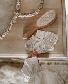 a person holding a wooden tray with white knitted items on it, including mittens and gloves