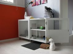 a small white dog sitting on the floor in front of a cabinet with its door open