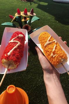 two people holding up plates with food on sticks in front of some flowers and grass