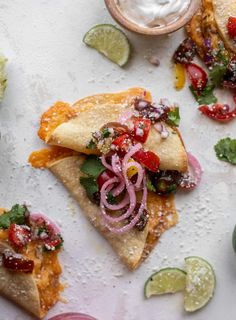 two pieces of flatbread with toppings on a white surface next to other food items