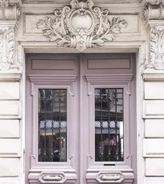 an old building with two double doors and flowers in the window boxes on the sidewalk