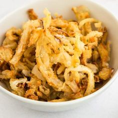 a white bowl filled with fried food on top of a table