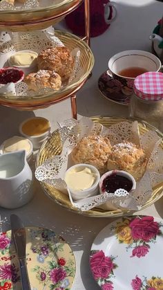 three trays filled with different types of food on top of a table next to cups and saucers