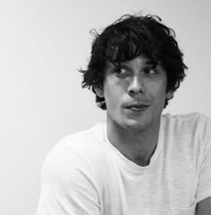 black and white photograph of a young man with curly hair wearing a t - shirt