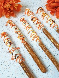 seven decorated sticks sitting on top of a table next to some orange and white flowers