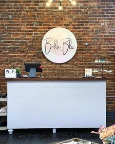 the reception table is set up in front of a brick wall with a sign above it