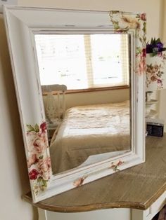 a mirror sitting on top of a wooden table next to a bed in a room