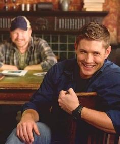 two men sitting at a table smiling for the camera