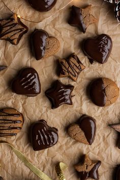 chocolate hearts and star shaped cookies are arranged on wax paper with pine cones in the background