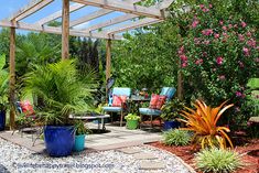 a patio with chairs, tables and plants in the middle is surrounded by trees and shrubs