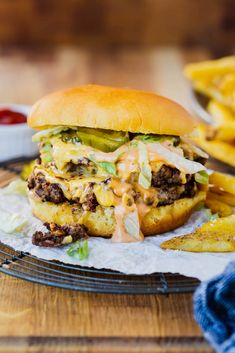 a cheeseburger with pickles and onions on a plate next to french fries