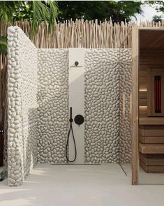 an outdoor shower with white pebbles and black faucet