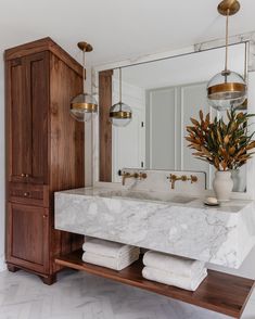 a bathroom with marble counter top and wooden cabinet in the corner, along with two hanging lights