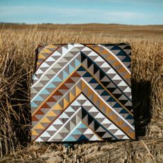 a patchwork quilt sitting on top of a dry grass field in the middle of nowhere