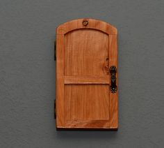 a wooden door on the side of a gray wall with a black handle and latch