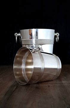 two metal buckets sitting on top of a wooden table