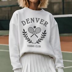 The Denver Tennis Club Sweatshirt, a timeless fusion of vintage charm and preppy style. Elevate your casual wardrobe with this meticulously crafted Vintage Tennis Crewneck, designed for both comfort and a touch of retro sophistication. ABOUT THIS ITEM: * Gildan Brand Crewneck Sweatshirt * 50% cotton, 50% polyester * Medium-heavy fabric  * Loose fit SIZING: * Please refer to the last photo for sizing measurements!  * Runs true to size, sizes are unisex * For oversized fit, size up 1-2 sizes PRODUCTION & SHIPPING: * Each item is made to order * Please allow a total of 5-8 business days for production and shipping RETURNS & EXCHANGES: * As each sweatshirt is custom printed exclusively for you, we do not accept returns or exchanges. * In the event of any issues with your shirt, please reach ou White Classic Sweatshirt For Spring, Classic White Sweatshirt For Spring, Classic White Spring Sweatshirt, Collegiate Graphic Print Sweatshirt For Spring, College Retro Sweatshirt, Classic White Sweater With Letter Print, Classic White Letter Print Sweater, Classic White Sweatshirt For College, Preppy Crew Neck Sweater For Spring