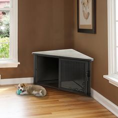 a dog laying on the floor in front of a small cabinet with its mouth open