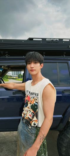 a young man standing in front of a blue truck