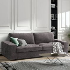 a living room with a gray couch and rugs on the floor in front of white walls