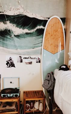 there is a surfboard hanging on the wall next to a bed and other items