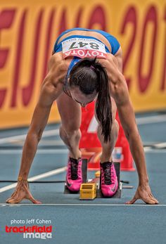 a woman is bent over on her knees while standing on one leg in the middle of a race