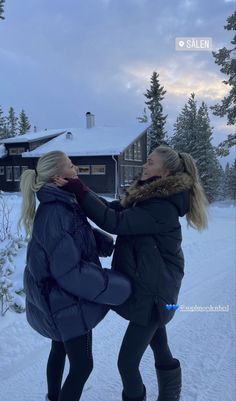 two women standing in the snow with their hands on each other's back legs