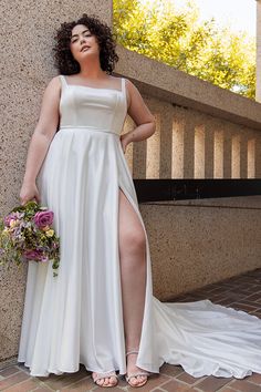 a woman in a white dress standing next to a wall