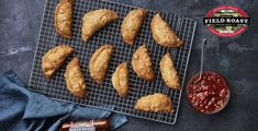 several pastries are on a cooling rack next to some chili sauces and bread