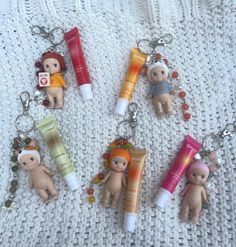 four little doll keychains with various items in them sitting on a white surface