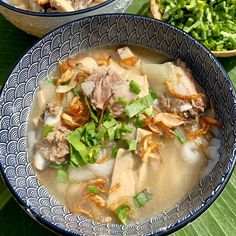 two bowls filled with meat and vegetables on top of a green leafy tablecloth