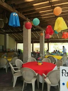 tables and chairs are set up with red tablecloths, paper lanterns hanging from the ceiling