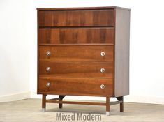 a wooden dresser sitting on top of a hard wood floor next to a white wall