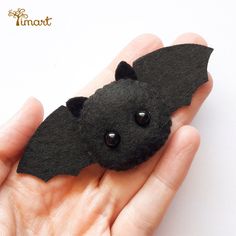 a hand holding a black bat brooch