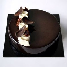 a chocolate cake with white frosting and pecans on the top is sitting on a black plate