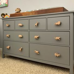 a gray dresser with toy animals on it