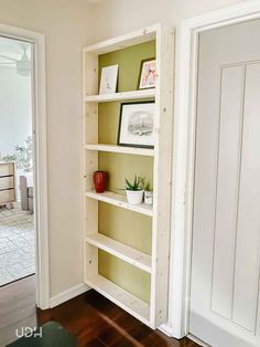 an empty bookcase in the corner of a room with white walls and wood floors