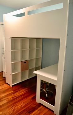 a white loft bed with built in desk and shelves