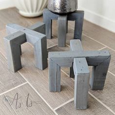 three wooden stools sitting on top of a tile floor next to a potted plant