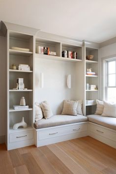 a white couch sitting in front of a book shelf filled with lots of books next to a window