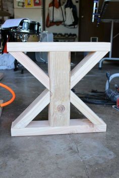 a wooden table sitting on top of a floor next to a pair of wrenches