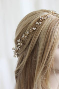 a woman with blonde hair wearing a gold headband and flowers on it's head