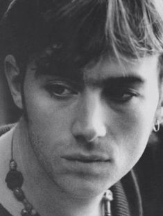 black and white photograph of a young man wearing a necklace with beads around his neck