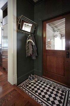 an entryway with a coat rack, mirror and checkered rug on the floor