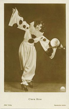 an old photo of a woman dressed in costume and holding a large white flag with black polka dots on it