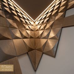 an abstract wooden sculpture with light coming from the top and bottom, in front of a white wall