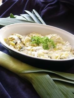 a white bowl filled with food on top of a green leafy table next to a blue cloth